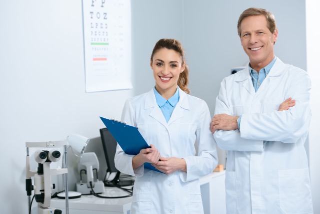 Smiling Ophthalmologists standing with diagnosis, in clinic