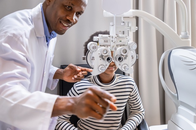 man optometrist using phoropter in clinic or optical shop.